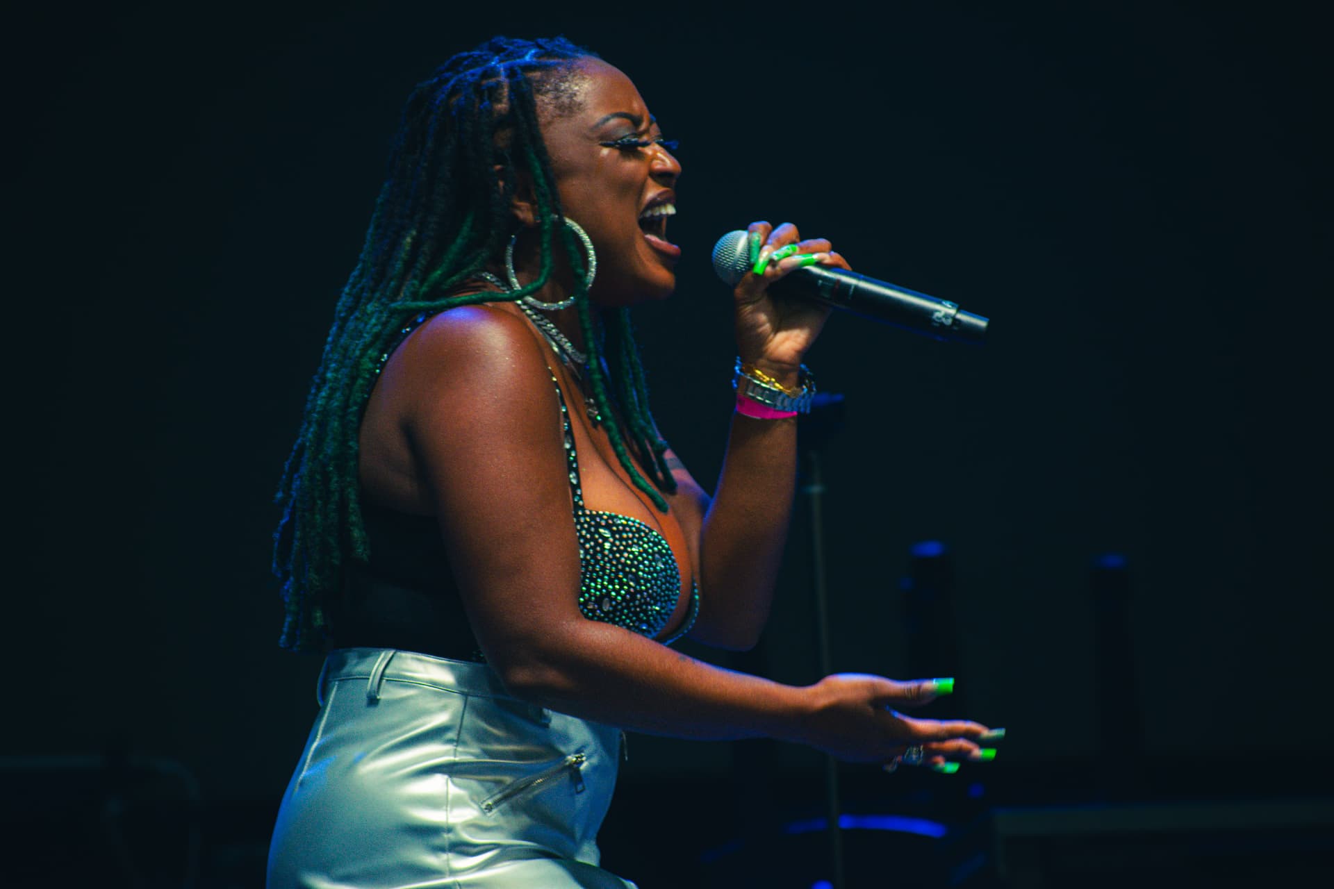 Emani singing live on stage into a handheld microphone